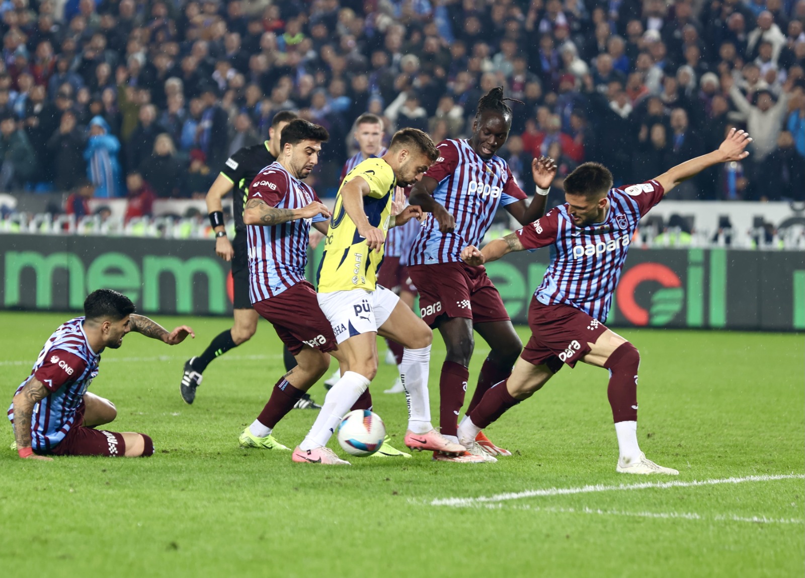 Uğur Meleke: Trabzon'un Fenerbahçe karşısındaki iştahlı-tutkulu oyununu görünce hafızam beni ister istemez Şenol Güneş’in ilk kez sahaya çıktığı Beşiktaş maçına götürdü. O maçta çok erken 10 kişi kalıp sadece savunma yapmışlardı ama o müsabakadaki iştahları, mücadele seviyeleri vardı dün de sahada. Trabzonspor’u Beşiktaş’la Fenerbahçe maçlarında izlediğinizde muhtemelen zirve yarışı yaparlar diye düşünürsünüz. Ancak Gaziantep, Hatay, Göztepe maçlarındaki hallerine bakınca orta sıra takımı zannedersiniz! Mesela dünün bordo mavililer adına en iyilerinden, dört net pozisyona giren, penaltı kazanan Okay Yokuşlu, bir de Beşiktaş maçında bu motivasyon seviyesindeydi. Ama lig sadece bu büyük maçlardan ibaret değil. Fenerbahçe içinse ilk 65-70 dakikası oldukça problemli geçen ancak oyuncu değişiklikleri sonrası ibrenin lehlerine döndüğü bir gündü. Şenol Güneş mücadele gücü bu derece yüksek, en üst seviye stresli bir günde 88 dakika oyuncu değiştirmedi (ya da kulübesi yetersiz olduğu için değiştiremedi). Jose Mourinho ise takımı iki penaltıyla 2-1 geriye düştüğü sırada kaliteli kulübesine başvurdu, oyuna sonradan giren Dzeko’nun, İrfan Can’ın, Filip Kostic’in hepsinin maçın kaderine tesir ettiğini söyleyebiliriz rahatlıkla. Bu isimlerin yanı sıra maça ilk 11’de başlayan ve savunmada-hücumda olağanüstü mücadele eden En-Nesyri de dünün en iyilerindendi. (Hürriyet)