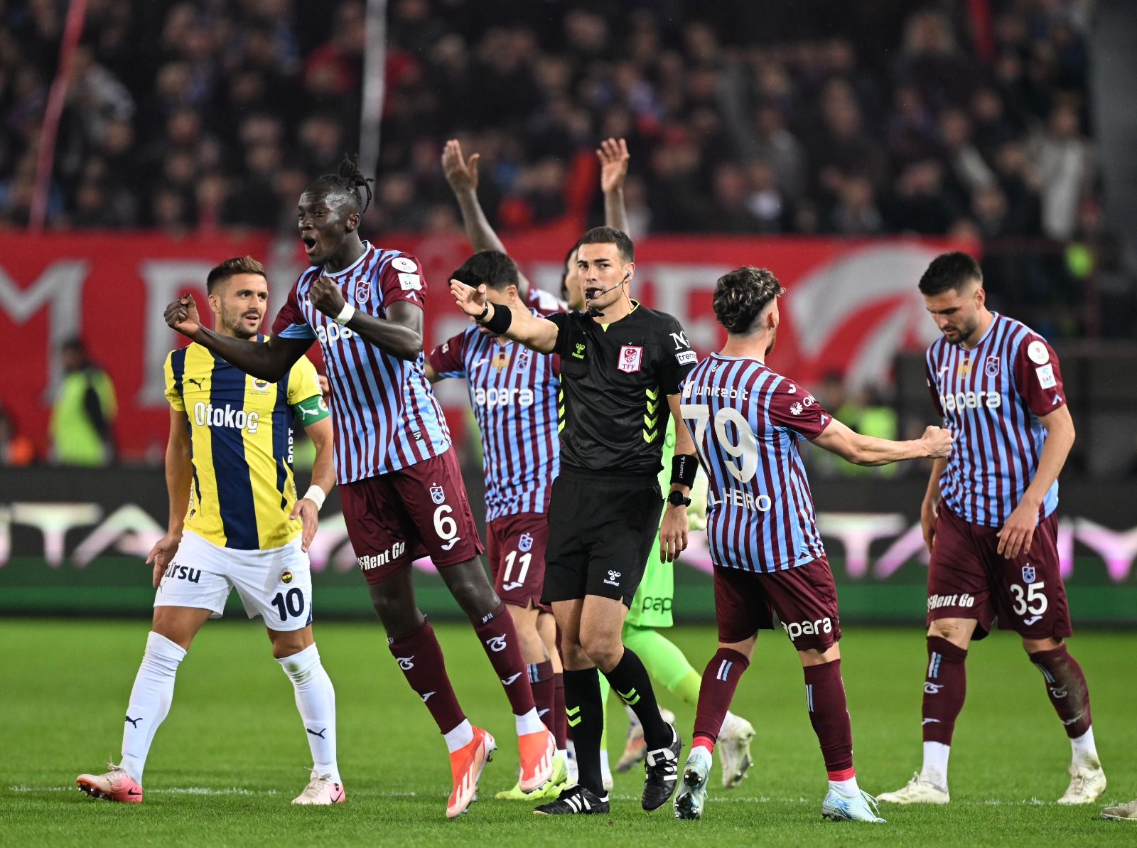  Bülent Timurlenk: Genç bir hakem, karmaşık pozisyonların içinde boğuldu kaldı. Bu, çıkan kararlar yanlış demek değil. Ev sahibinin iki penaltı golü ve Dzeko'nun sayısı. İki kalecinin nefis kurtarışları olmasa en az 4 gol daha izlerdik. Çok rahat geçilen orta sahalar, iki kanadının yaş toplamı 69 olan Trabzonspor ve defans göbeği çok dağınık olan Mourinho'nun takımı. VAR artı sakatlıkla sadece bir pozisyonda oyunun 7 dakika durduğu gerilimi yüksek, tecrübesiz olunca futbolcuların da üzerine oynadığı bir genç hakemin altından kalkamadığı bir maç izledik. Mourinho'nun ikinci yarıdaki hamleleri geç de olsa sonuç getirdi. Geçen sezon 3-2 biten maçta tabelayı Batshuayi değiştirmişti. Bu sefer de Amrabat… Fenerbahçe için 3 puandan çok daha fazlası. (Sabah)